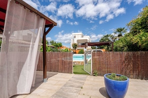 A backyard with a pool, a pergola, a wooden fence, and a large planter. - Gîte Navacelles (Lavérune)