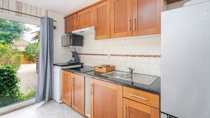 Une cuisine avec des meubles de rangement en bois, un four à micro-ondes, un évier et un réfrigérateur.