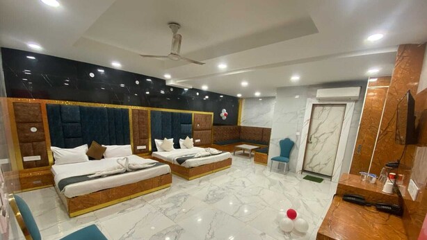 Una habitación de hotel con dos camas, zona de estar, baño y mostrador de recepción.