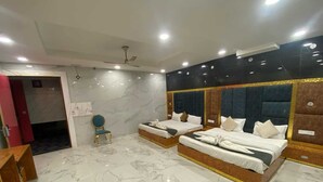 Habitación de hotel con dos camas, suelo de mármol, ventilador de techo y una silla.