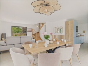 Un comedor moderno con una mesa de madera, sillas blancas y una lámpara de techo original.