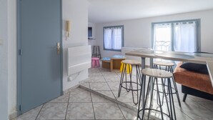 A kitchen with a dining area, a blue door, and a window with curtains. - Le Nid de Pézenas - Centre de Pézenas (Pézenas)
