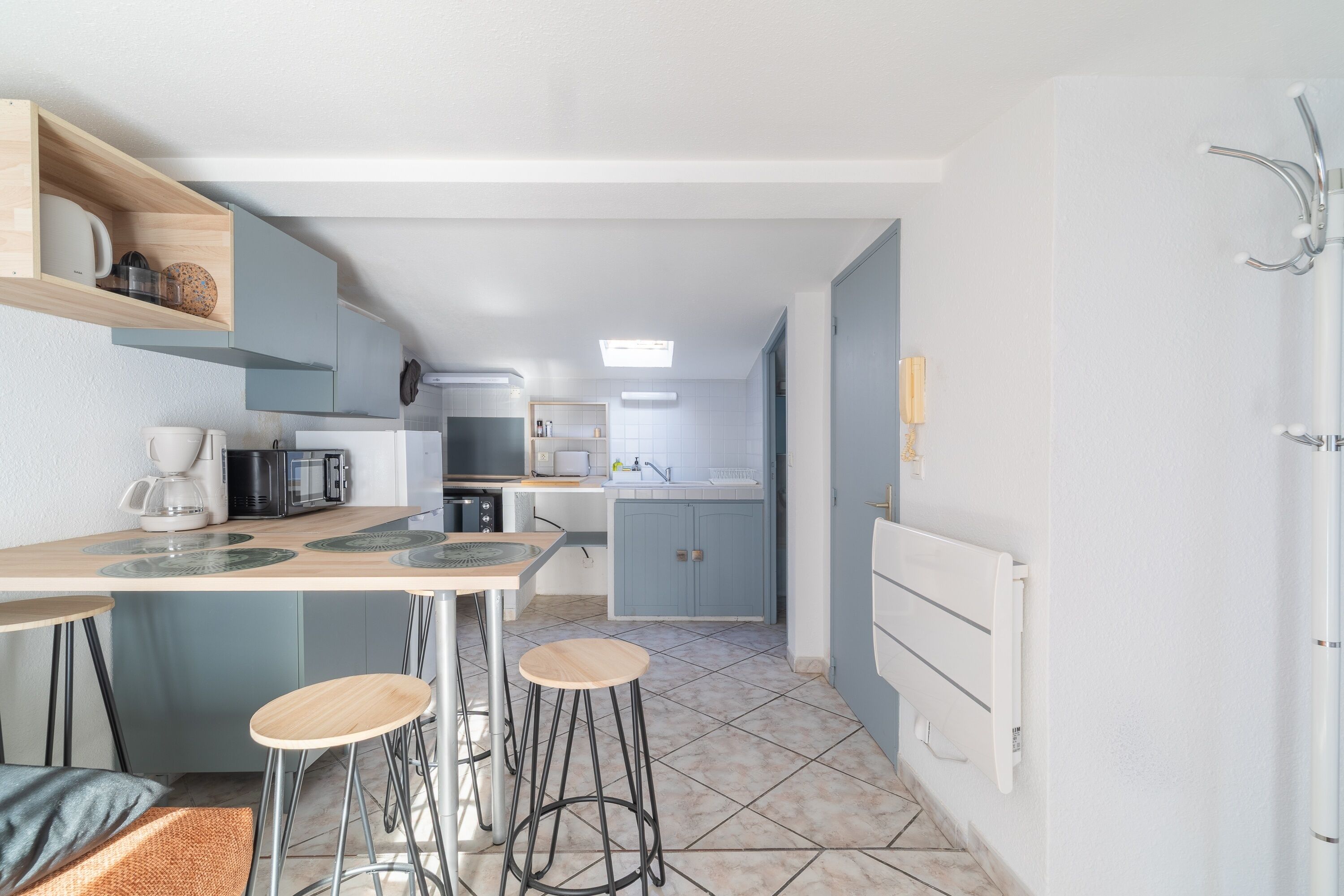 Uma cozinha compacta com uma ilha central, banquetas de bar e uma área de refeições.