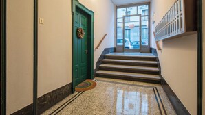 Ein Flur mit einer grünen Tür, einer Treppe und einem Teppich mit Muster.