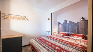 Una camera da letto con un letto, un appendiabiti in legno, una lampada a parete e una testiera in legno.