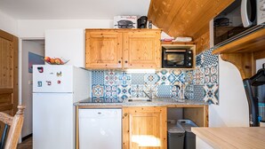 Cucina compatta con mobili in legno, forno a microonde, lavastoviglie e schienale piastrellato.