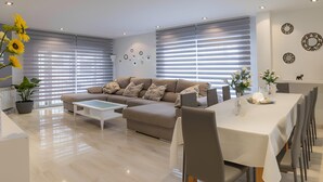 A modern living room with a beige sofa, a coffee table, and a dining area with a table and chairs. - YOUR OASIS NEAR MADRID WITH A HOT TUB AND SWIMMING POOL. (Villarejo de Salvanés)