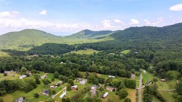 An aerial view of a rural area with scattered houses, roads, and green hills.