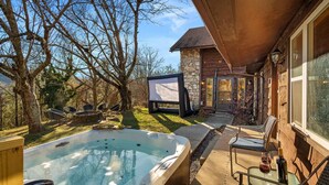 Un jacuzzi, mobiliario exterior y un edificio de piedra con una terraza de madera.