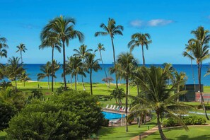 Tropical beachfront property with swaying palms, an oceanfront swimming pool, and tennis courts set against lush landscaped lawns and blue Pacific waters. - One bedroom, two bath condo at the Maui Sunset. (Kihei)