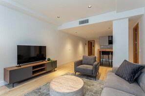 En moderne stue med et fladskærms-tv, en grå sofa og en lænestol.