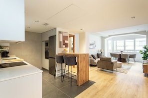 A modern kitchen with a central island, bar stools, and a dining area with a table and chairs. - Enjoy a comfortable and modern stay in this bright apartment located on the fifth floor of a building with an elevator, on the central Félix Boix street and just a 5-minute walk from Plaza de Castilla. (MADRID)