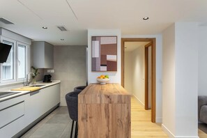 A modern kitchen with a wooden island, grey cabinets, and a bowl of fruit on the counter. - Enjoy a comfortable and modern stay in this bright apartment located on the fifth floor of a building with an elevator, on the central Félix Boix street and just a 5-minute walk from Plaza de Castilla. (MADRID)