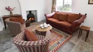 Ein gemütliches Wohnzimmer mit Kamin, einer Couch, gemusterten Sesseln und einem Couchtisch.