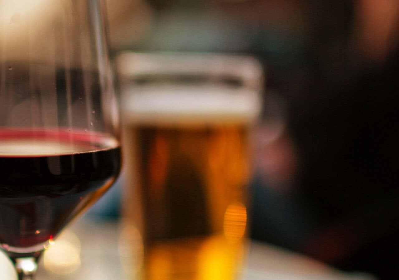 A glass of red wine and a beer mug on a table.