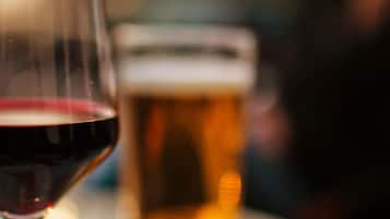 A glass of red wine and a beer mug on a table.