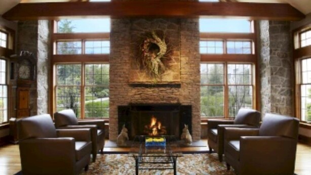 Una habitación amplia con chimenea de piedra, ventanas grandes y sillones de cuero.