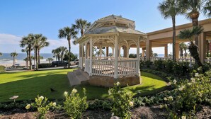 A gazebo with a white railing, surrounded by a well-maintained lawn and flowering plants. - San Luis 736 - Oceanfront Paradise (Galveston)