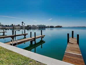 A calm waterfront with wooden docks and a grassy area. - Turtle Baycation (Rockport)
