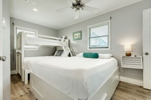 A bedroom with a bunk bed, a bedside table, a lamp, and a window with blinds. - Oceanfront Vista (Galveston)