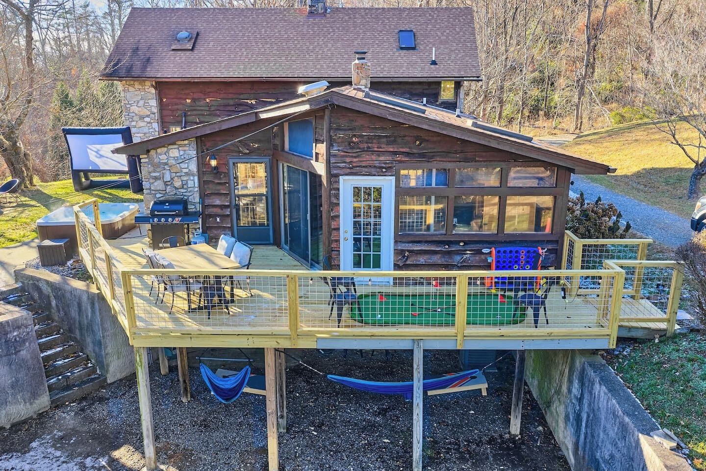Une cabane dotée d’une terrasse, de meubles de jardin, d’un bain à remous et d’une piscine.