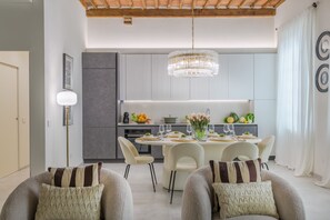 Un espace repas moderne agrémenté d’un lustre, de meubles de couleur grise et d’une table blanche dressée pour quatre personnes.