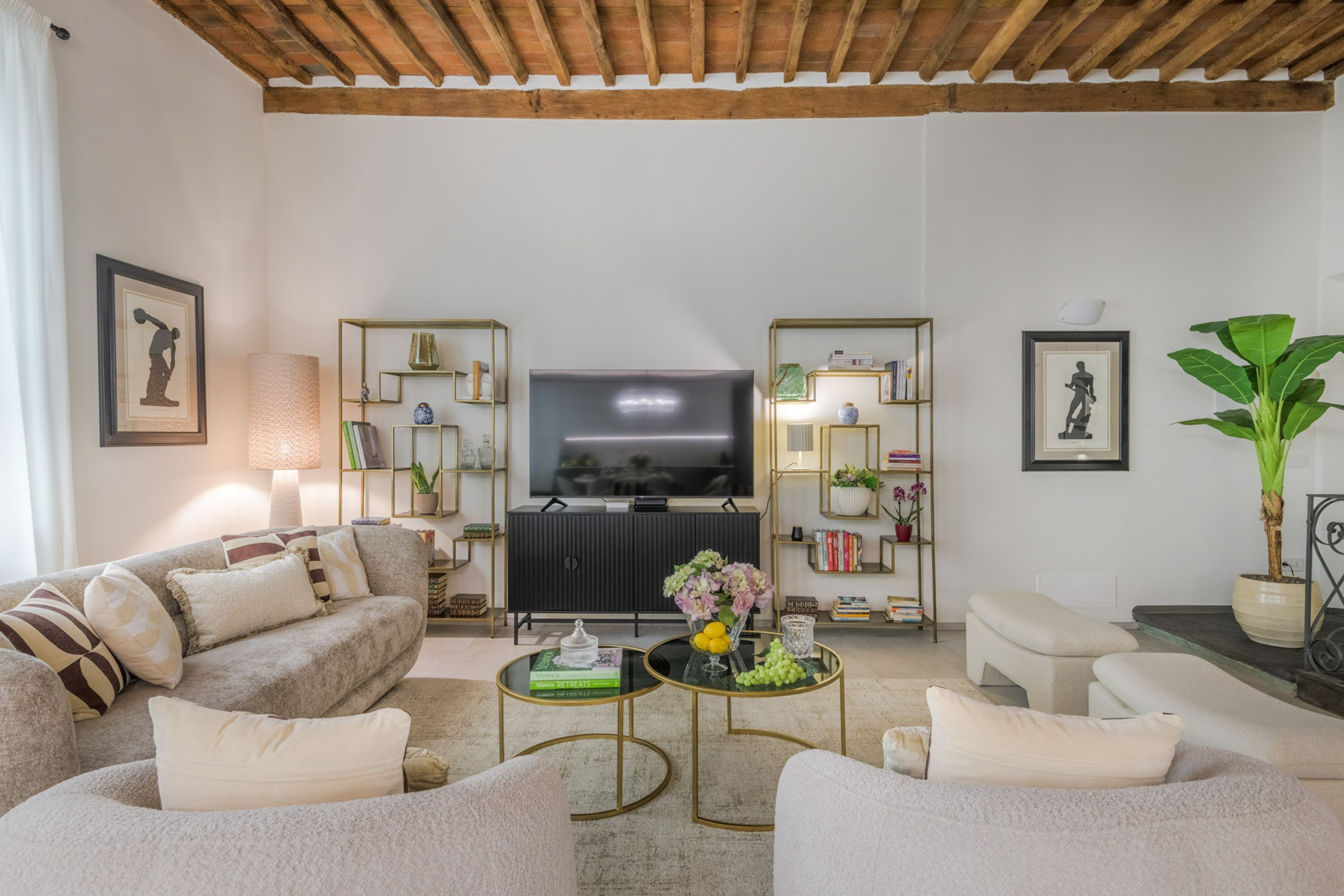 A living room with a sofa, armchairs, a TV, and decorative items.