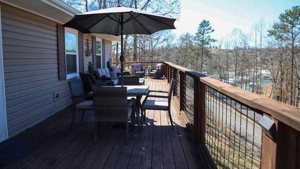A deck with outdoor furniture, a large umbrella, and a view of trees and buildings. - Lakeview LaFollette Retreat, Sleeps 10 - Game Room (LaFollette)