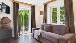 Ein modernes Wohnzimmer mit einer Couch, einem Fernseher und einem Fenster mit Vorhängen.