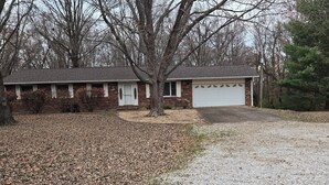 A two-story house with a garage, surrounded by trees and a gravel driveway. - Vintage Country Retreat and Peaceful (Freeburg)