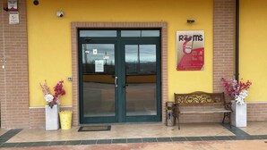 A hotel entrance with a glass door, a bench, and potted plants. - ROOMS DI MATTEO (San Paolo di Jesi)