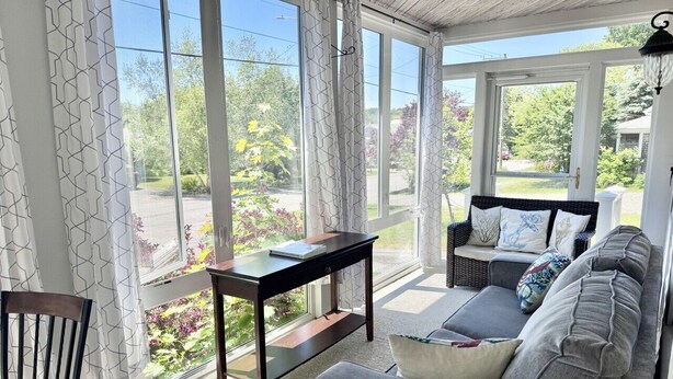 A sunlit room with a sofa, a table, and a chair.