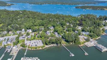 An aerial view of a coastal residential area with houses, a marina, and a large body of water.