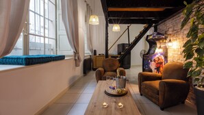 Un espacio de sala acogedor con un sofá, sillones, una mesa de centro de madera y una chimenea.