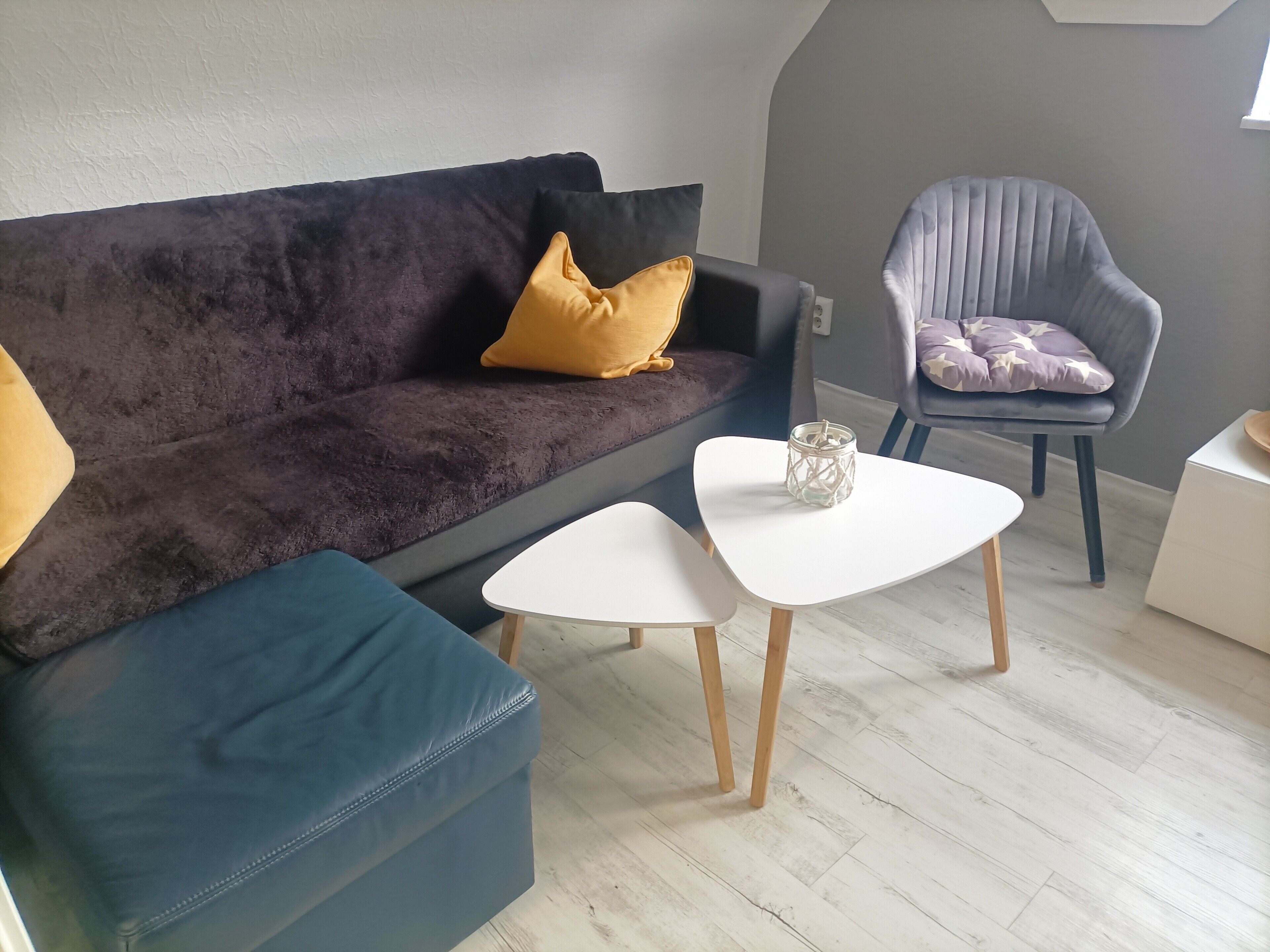 Ein modernes Wohnzimmer mit einem dunklen Sofa, einem blauen Sessel und einem weißen Couchtisch.