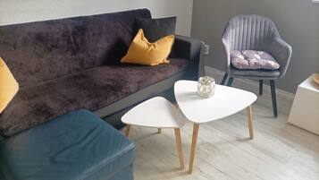 Ein modernes Wohnzimmer mit einem dunklen Sofa, einem blauen Sessel und einem weißen Couchtisch.