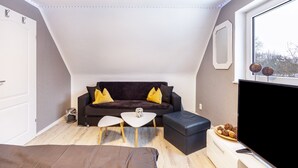 Ein modernes Wohnzimmer mit einem dunklen Sofa, einem weißen Couchtisch und einem Flachbildfernseher.