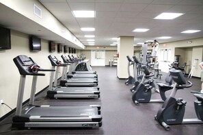 Ein Fitnessstudio mit Laufbändern, Crosstrainern und stationären Fahrrädern.