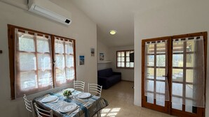 Comedor con mesa dispuesta para cuatro personas, un sofá y una puerta que da al exterior.