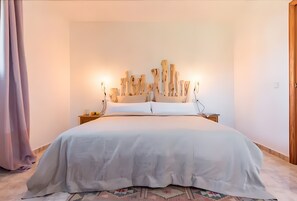 A bedroom with a large bed, a wooden headboard, bedside tables, and a patterned rug. - Villa 'Can Marsa' with Mountain View, Wi-Fi and Air Conditioning (Illes Balears)