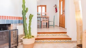 Un passadís amb una escala que mena a una zona de menjador, una porta de fusta i una planta en test.