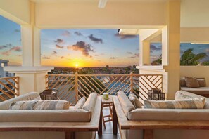 A rooftop terrace with a sunset view, wooden furniture, and a pool. - Bon Bida Penthouse with a spectacular panorama over the sea and beautiful sunsets (Kralendijk)