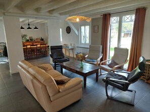 A spacious living room with a sofa, two armchairs, a coffee table, and a dining area in the background. - Holiday Home 'Bienvenue À La Maison' with Private Terrace, Garden & Wi-Fi (Mézos)