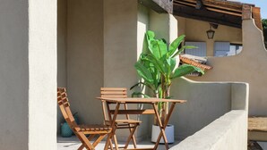 A patio with a wooden table and chairs, a potted plant, and a concrete wall. - Suite Evasion - Maison d'hôtes l'Espigoulié (Sainte-Maxime)