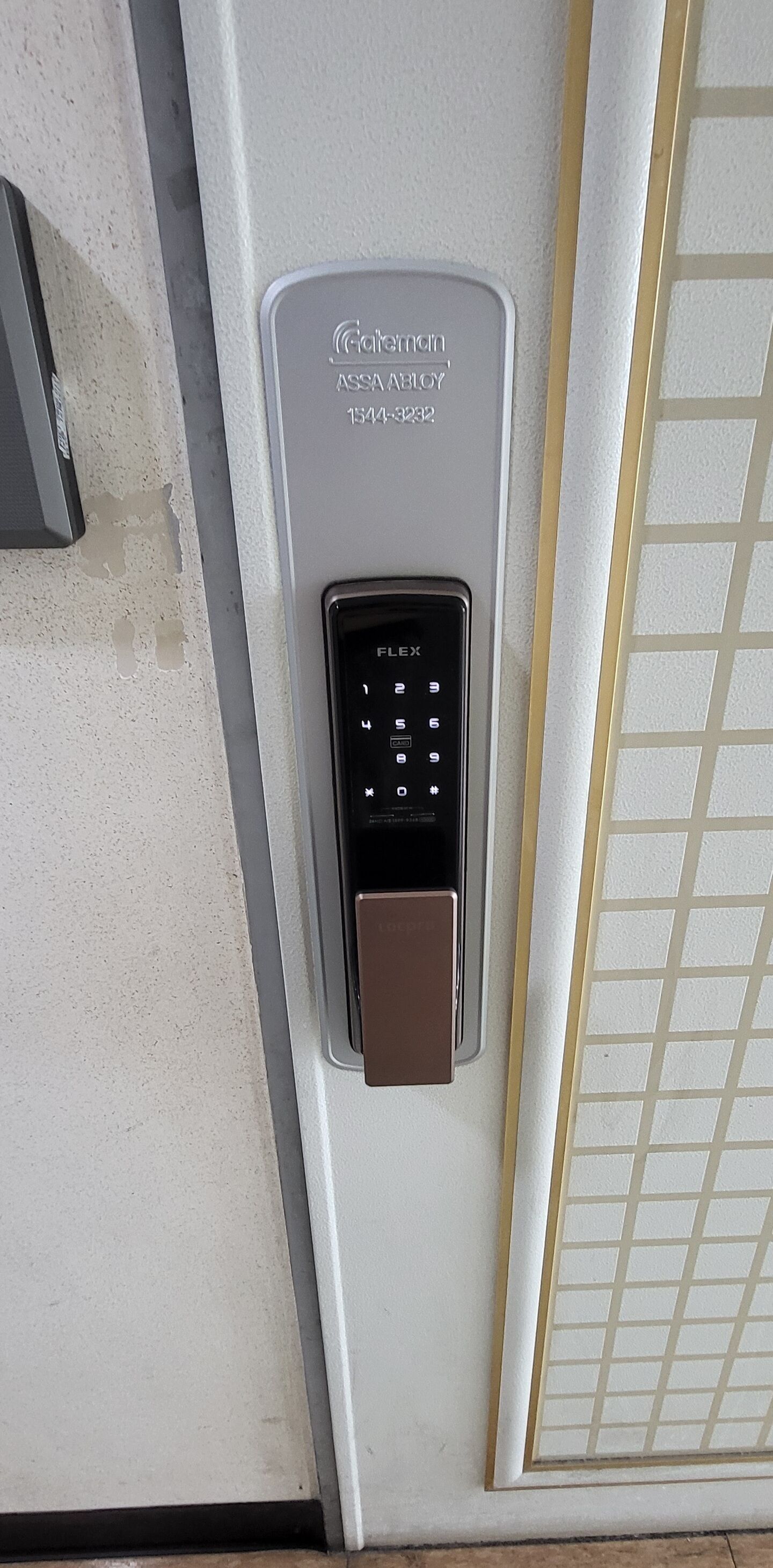 A digital keypad lock on a door, with a plaque above it.