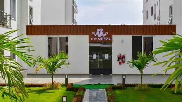 A fitness center with a modern design, featuring a prominent logo, a fire extinguisher, and a well-maintained outdoor area with plants and a pathway. - Charming apartment in fantastic Mombasa perfect for your getaway (Mombasa)
