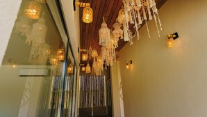 A hallway with wooden ceiling beams, hanging macrame chandeliers, and wall-mounted sconces. - Ayana Coral Bay Resort (Piatra-Olt)