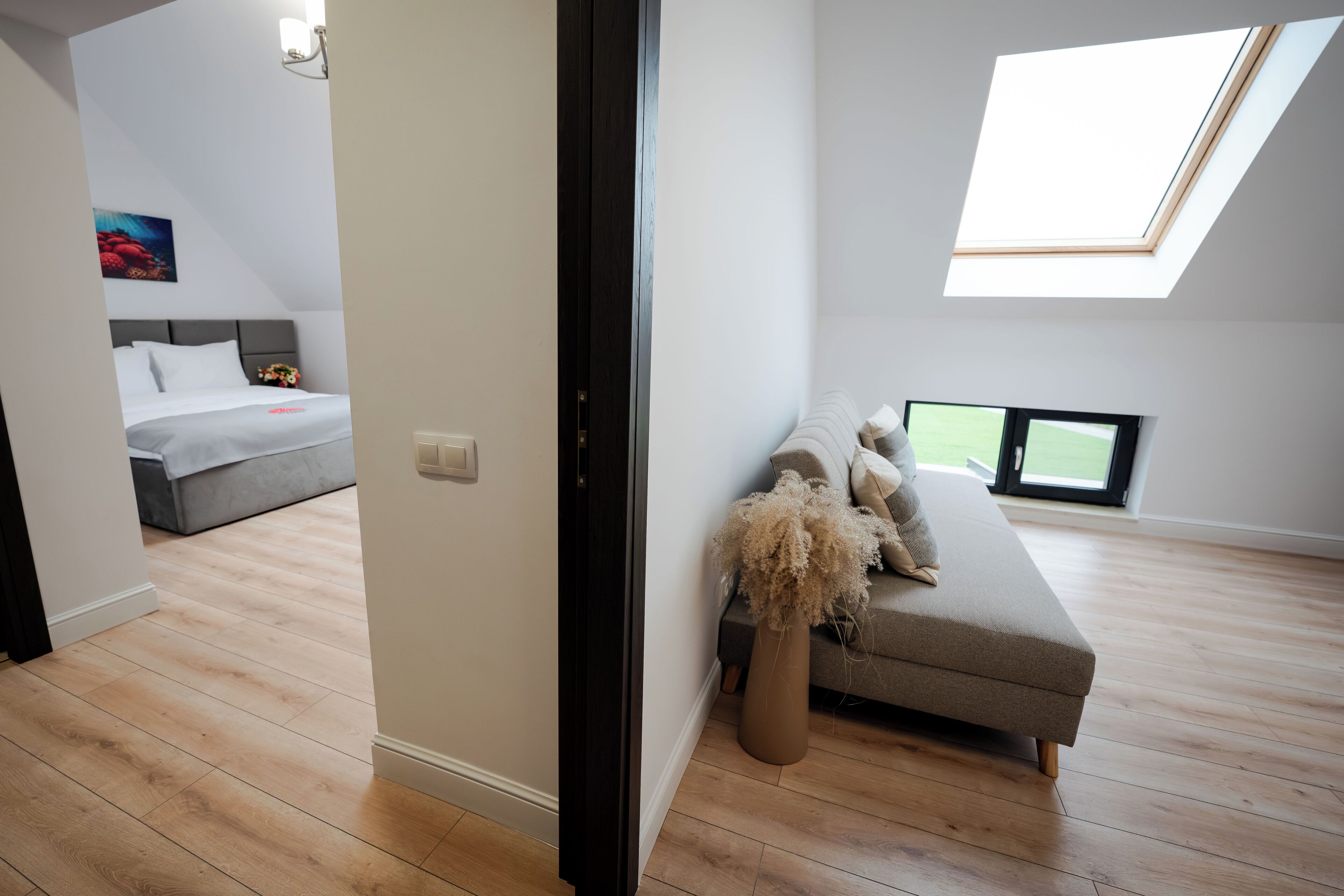 A modern bedroom with a skylight, a sofa, and a bed.