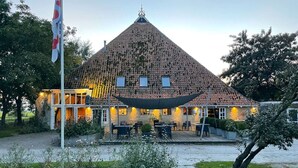 A building with a conical roof, outdoor seating area, and a flagpole. - Leien Tiny House in Weidum (Weidum)