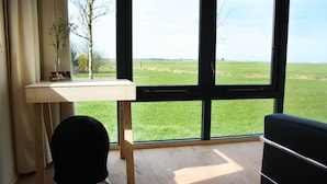 A room with a large window, a wooden desk, a black chair, and a black sofa. - Leien Tiny House in Weidum (Weidum)